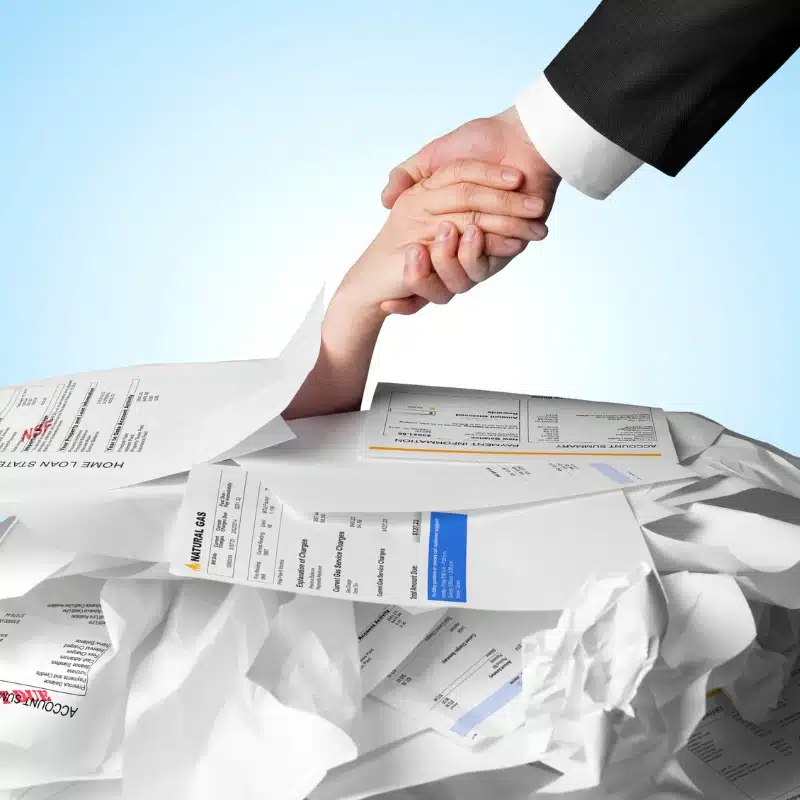 hand grasping another hand under a stack of bills